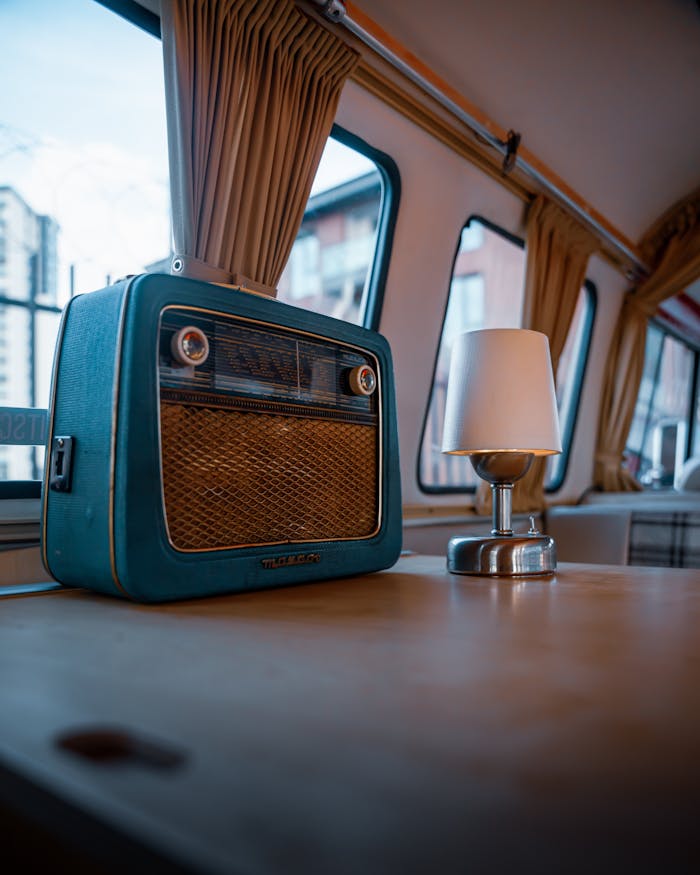 A classic vintage radio and modern lamp sit on a table in a retro camper setting, capturing nostalgic vibes.