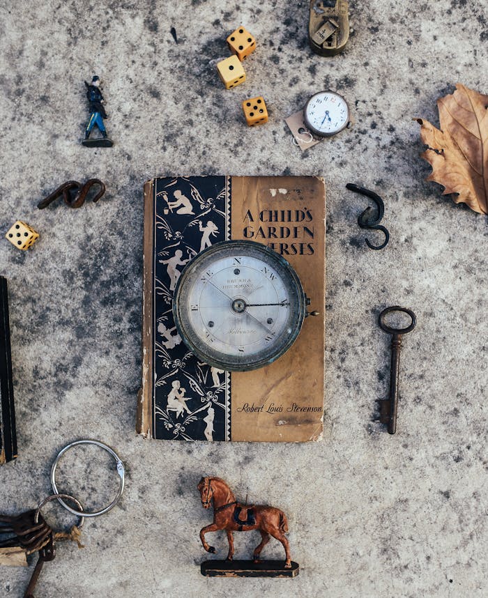 Flat lay of antique items and trinkets, featuring a vintage book and various small objects.